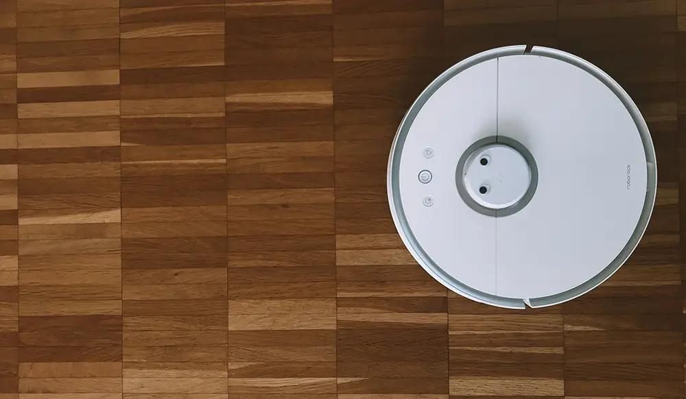 white robot vacuum cleaning hardwood floor
