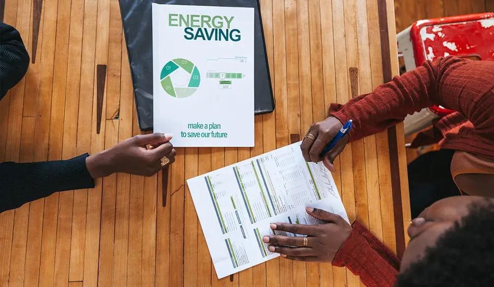A young woman financial advisor is helping a customer to sign a new contract about energy saving and green sustainable resources.